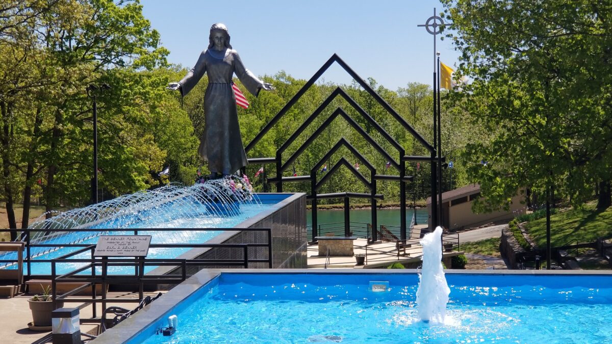 A silver sculpture of Mary near fountains and a metal structure.