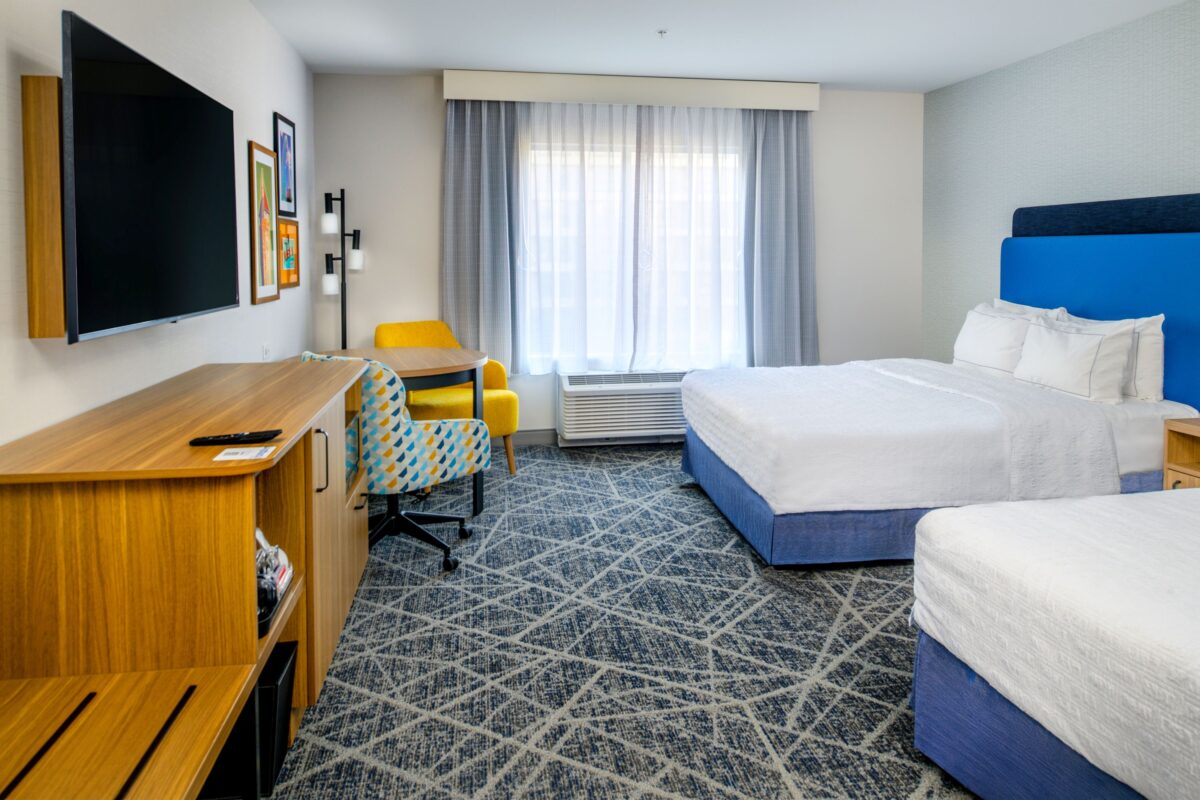 two bed guest rooms with tv and chair
