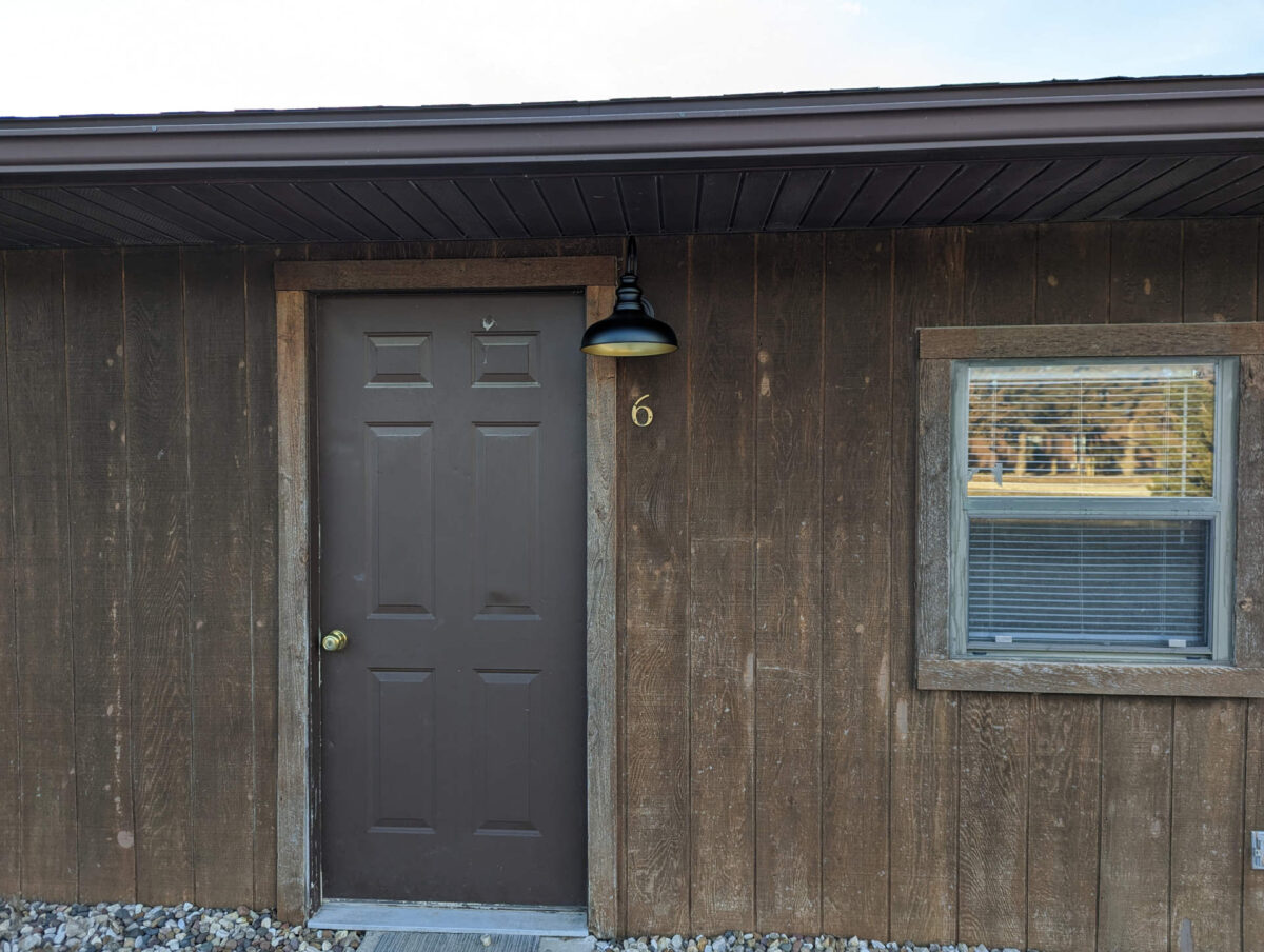 The exterior of a rustic cabin with brown exterior and door.