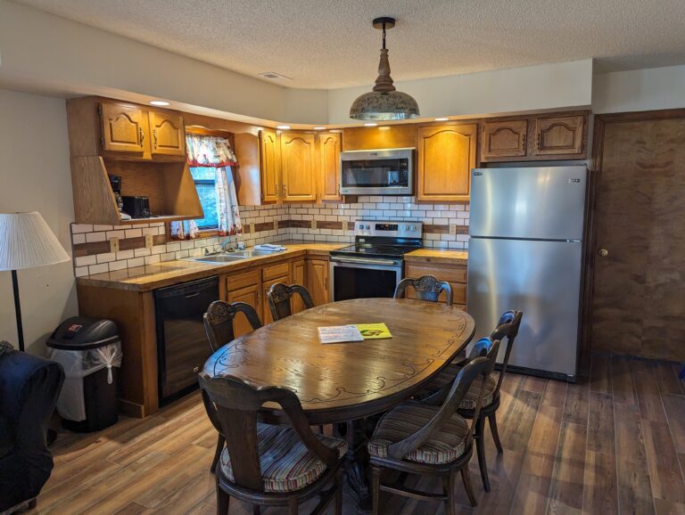 The furnished and warmly-lit kitchen of a cabin.