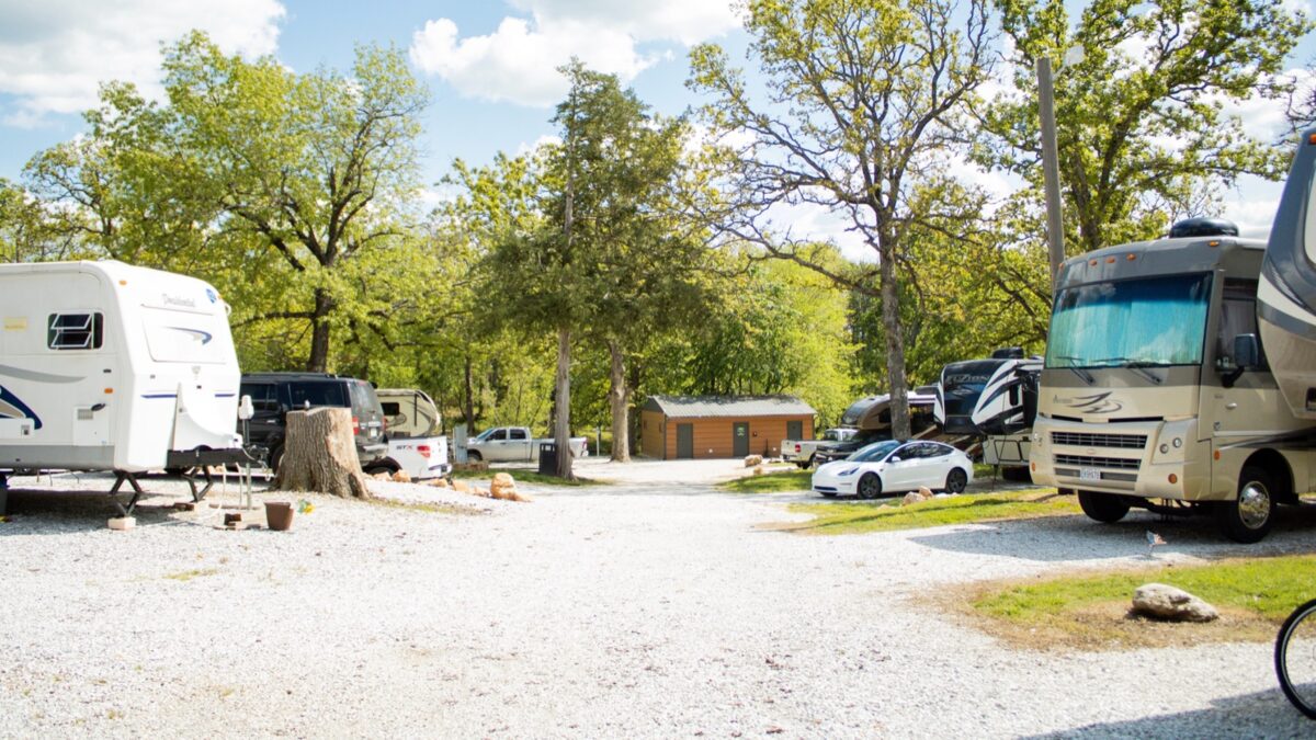 Campers and cars on a gravel lot.