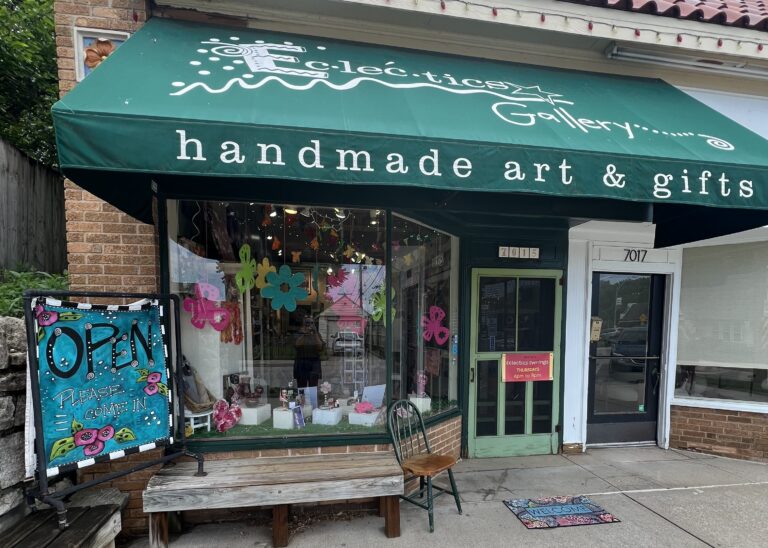 The exterior of a gift shop with window displays, signs and a green awning over the top.