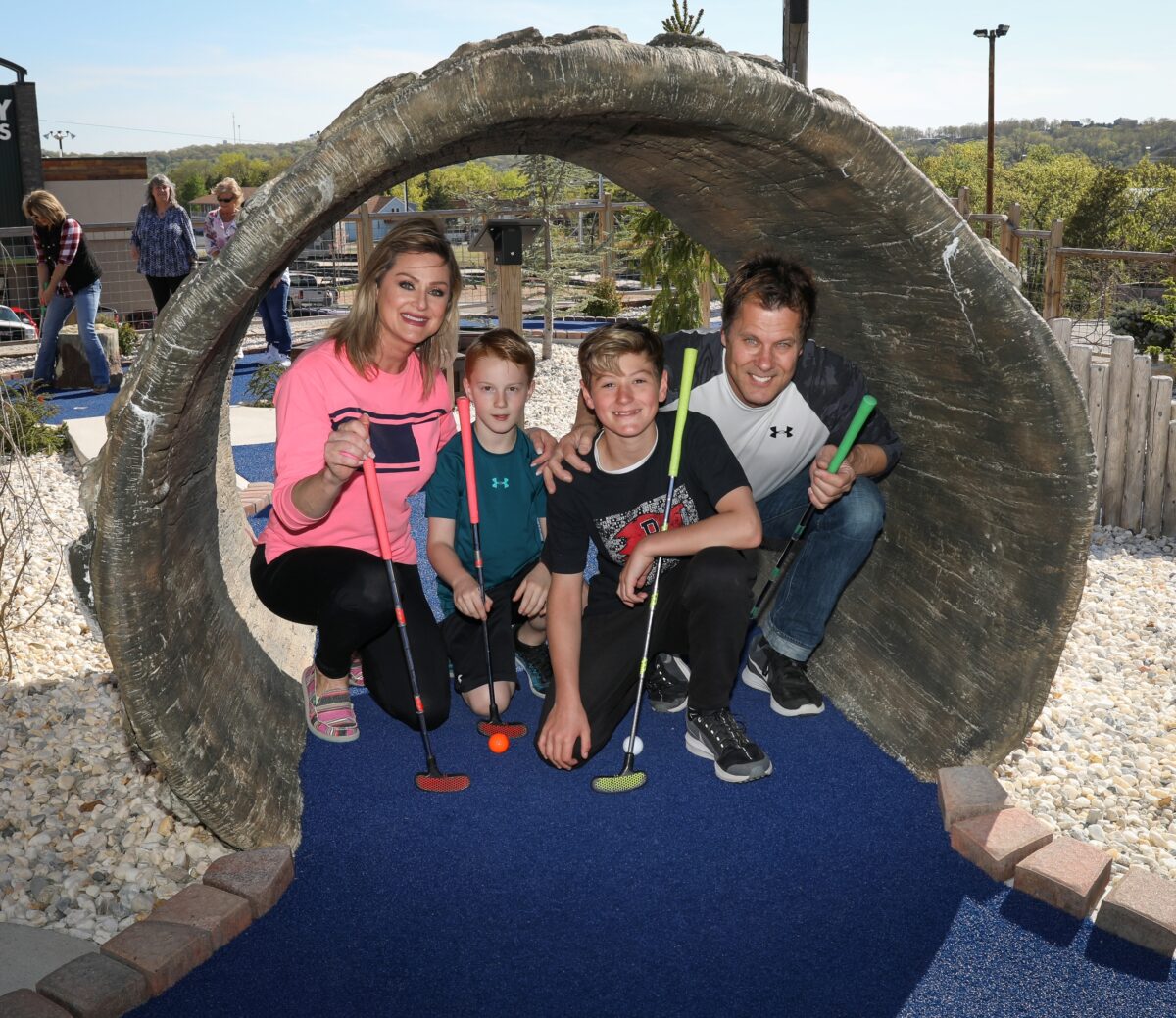 A family of four pose beneath an obstacle on a minigolf course.