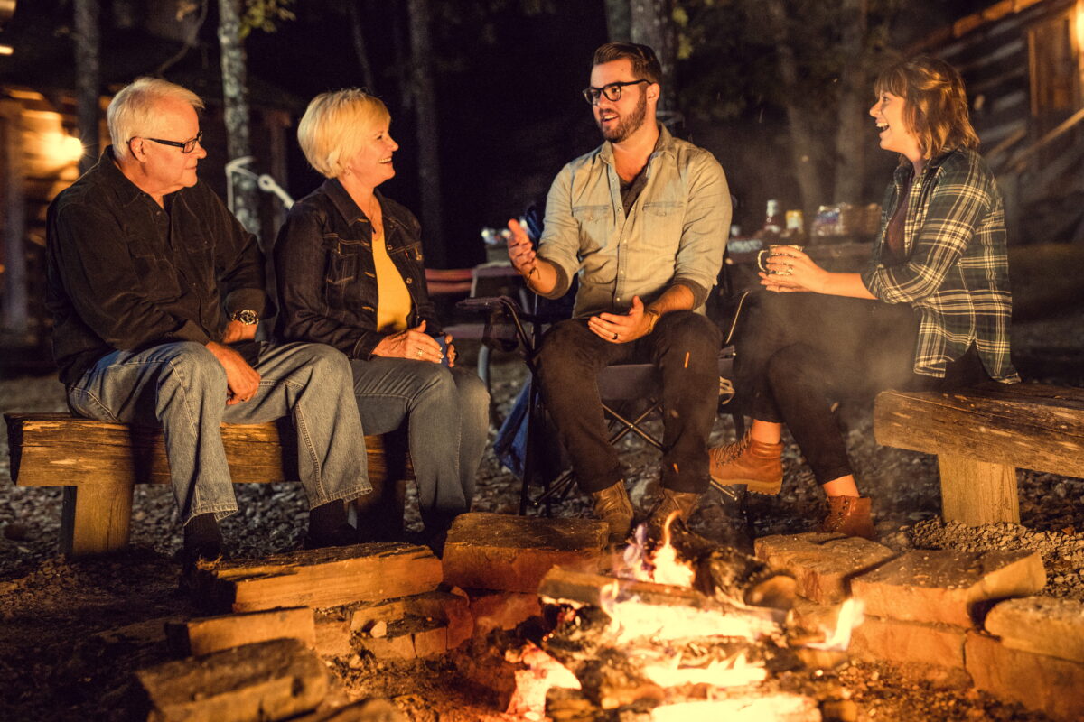 A family laughs around a campfire at Silver Dollar City Campground.