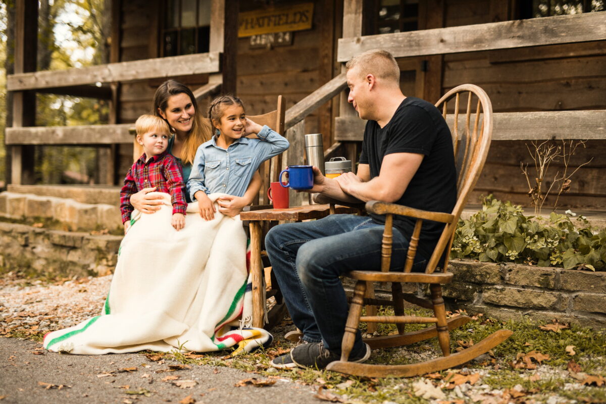 A family sits together outside a cabin at Silver Dollar City Campground.
