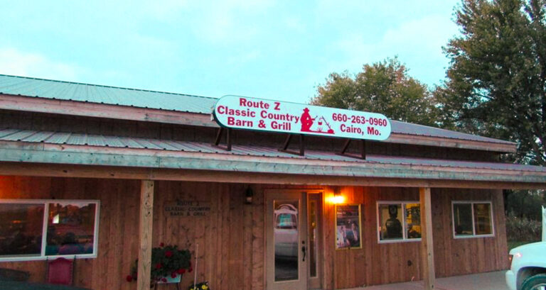 The outside of a country bar with wood aesthetics and a sign over the top.