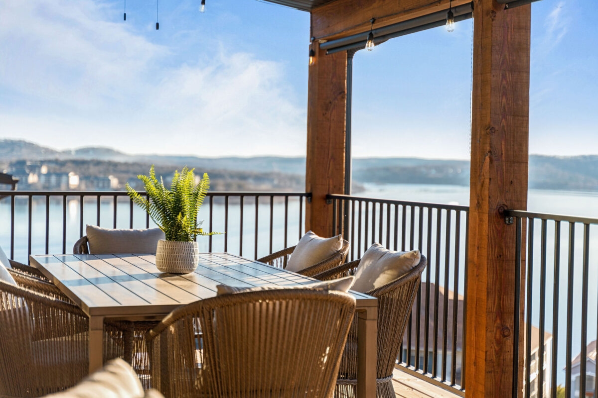 A deck with seating and a table overlooking a lake.