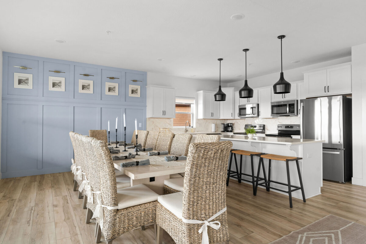 A ktichen and dining space with a bar top and stools, table and chairs and wood, white and blue tones.