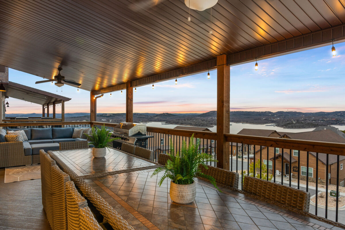 Tables and chairs on a deck outdoors overlooking the lake.