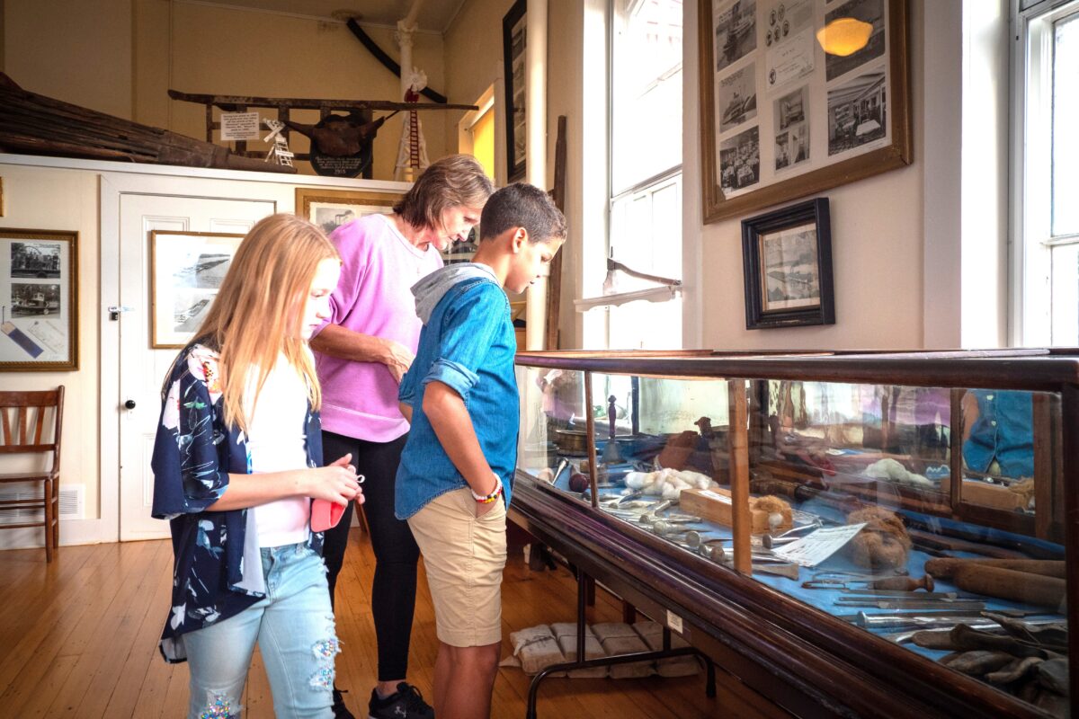 Three people peruse displays in a museum.