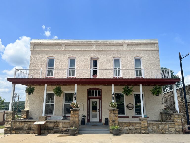 The exterior of a two-story tan hotel building on a sunny day.