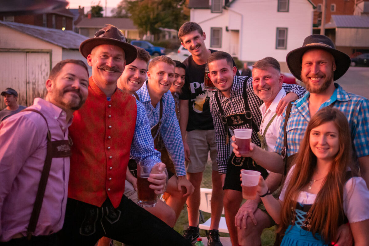 Un groupe de personnes met une photo avec de la bière à portée de main. Certaines personnes portent des vêtements allemands.