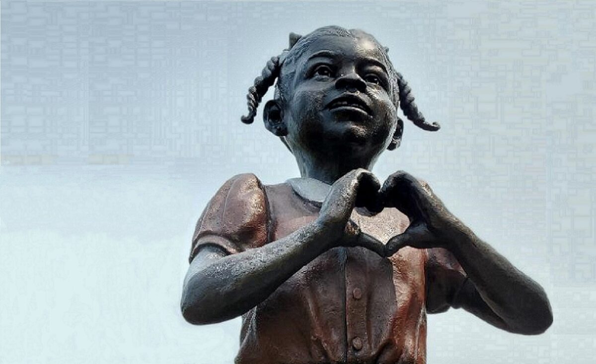 Part of one of the statues at Lincoln School, a young African- American girl making a shape of a heart with her hands.