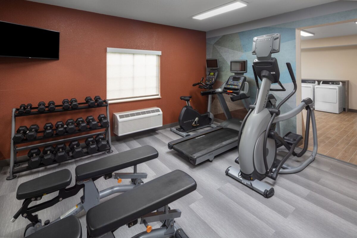 Fitness center with free weights, treadmill, elliptical and bike by the laundry room.