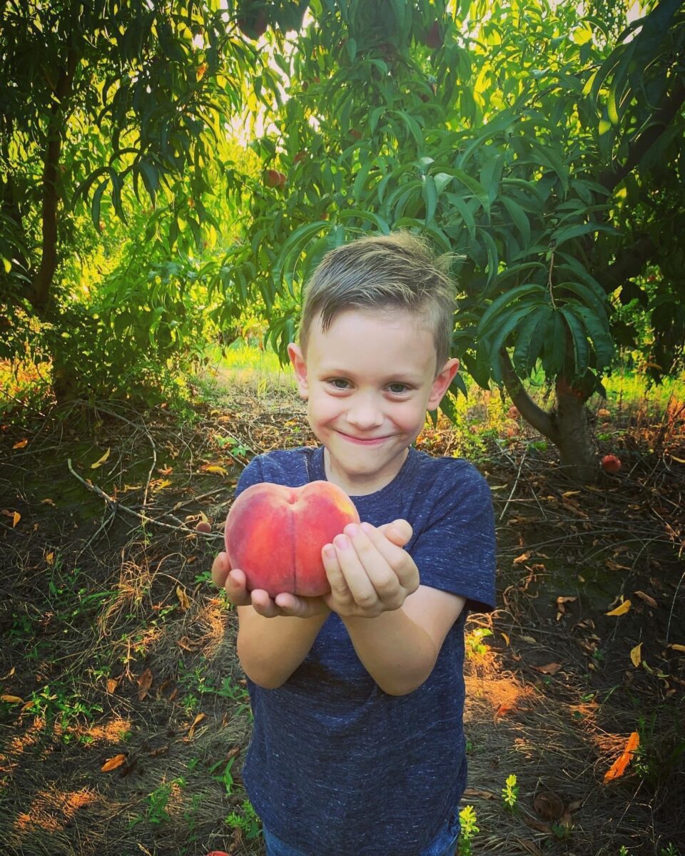 A child poses with an apple at Historic Weston Orchard and Vineyard.