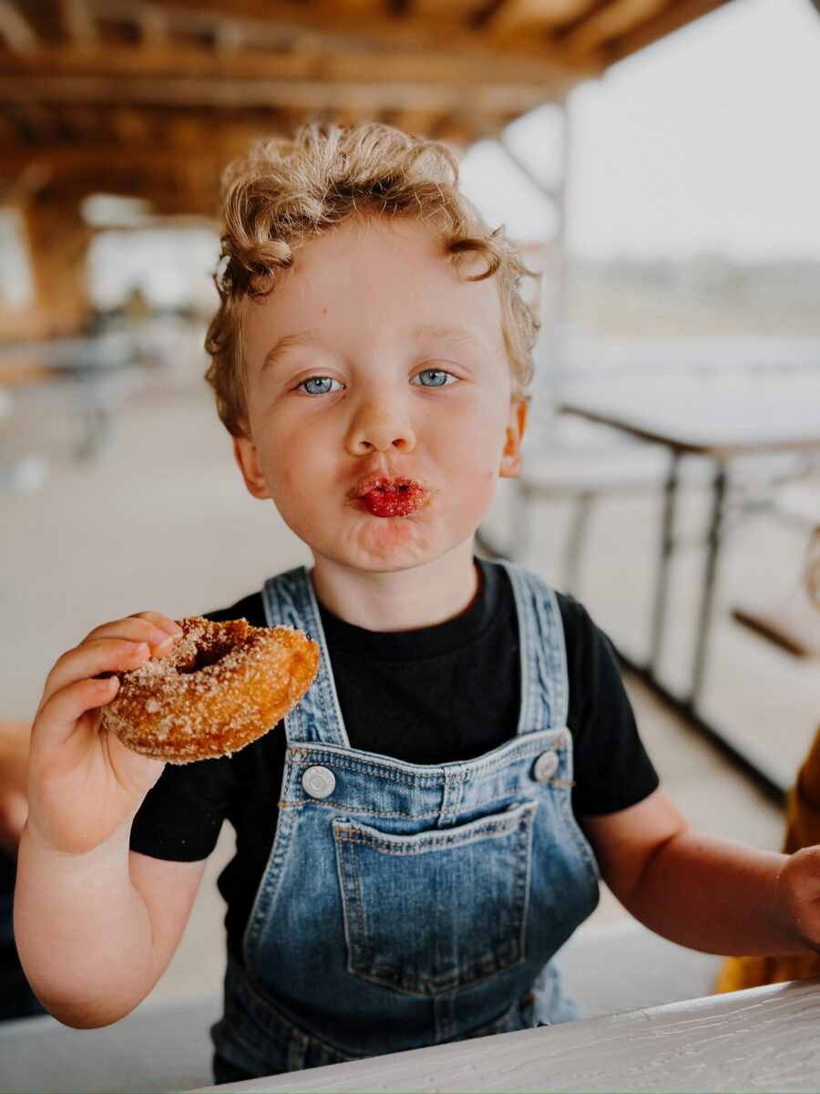A child eats a donut at the Historic Weston Orchard and Vineyard.