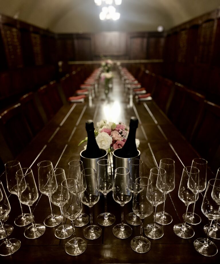Champagne flutes and two bottles chilling in ice on a long table.
