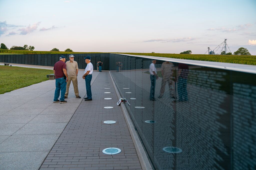Three men talk at Missouri's National Veterans Memorial in Perryville beside a full-sized replica of Washington, D.C.'s Vietnam Wall honoring those who served, lost their lives and went missing in the Vietnam War.