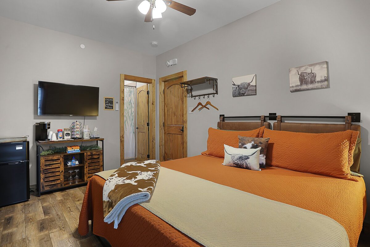 A rustic interior room with a bed decorated in orange.