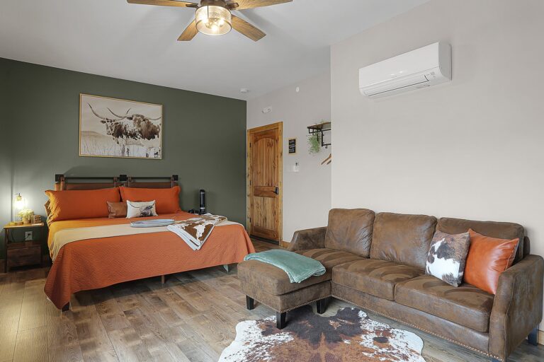 A rustic interior room with wood floors and a couch and bed.