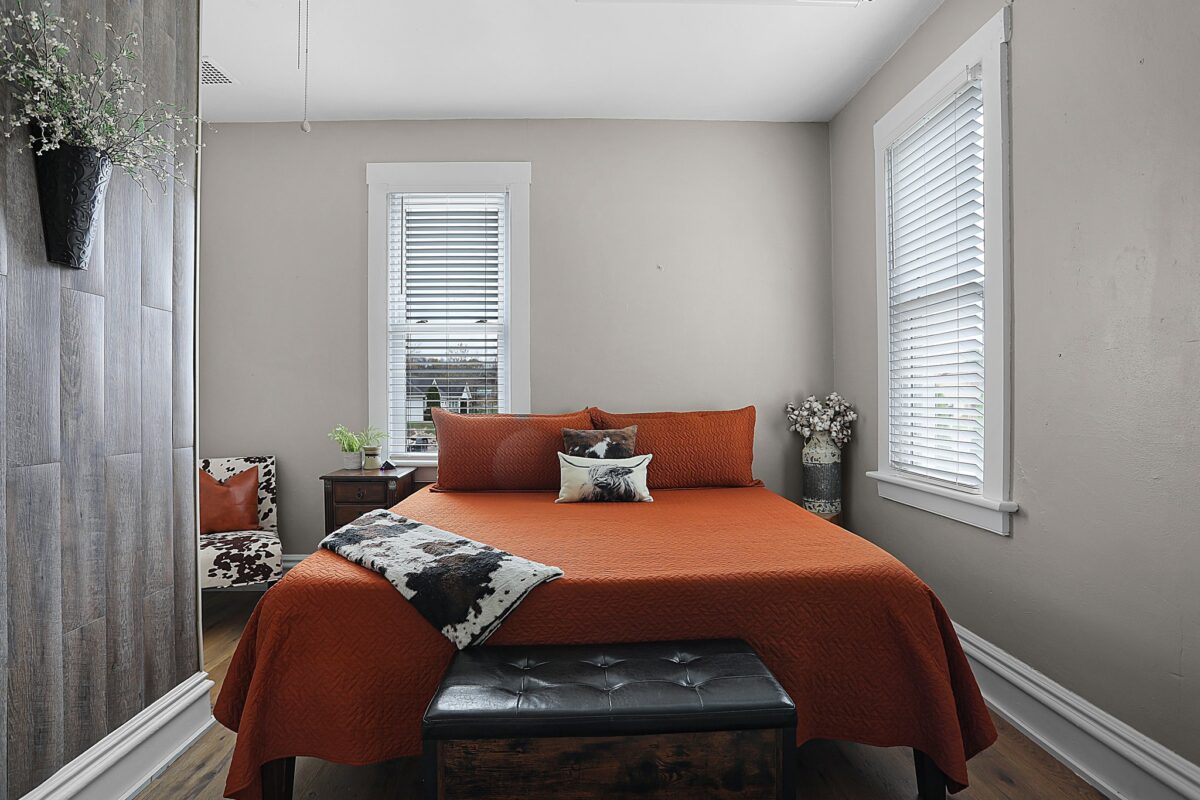 A rustic interior room with a bed decorated in orange.