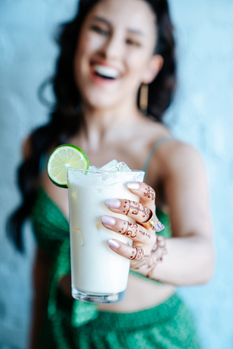 A woman holding a drink out toward the camera.