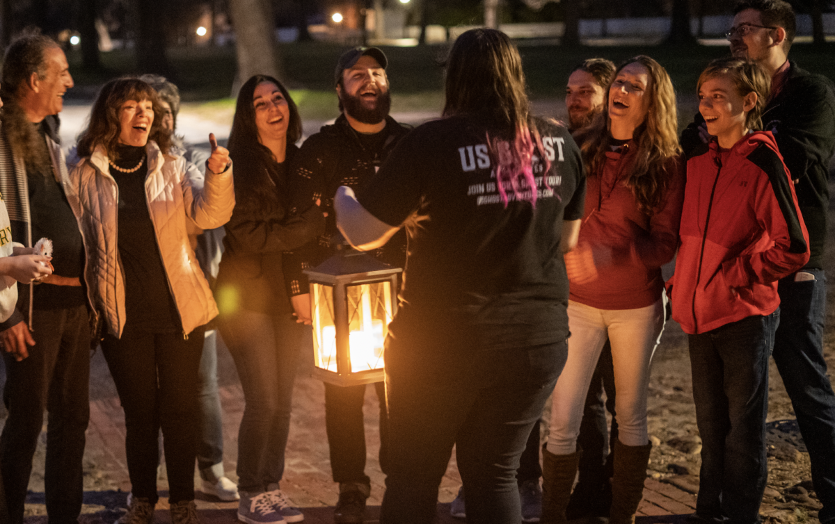 A tour guide with a lantern addressing attendees.