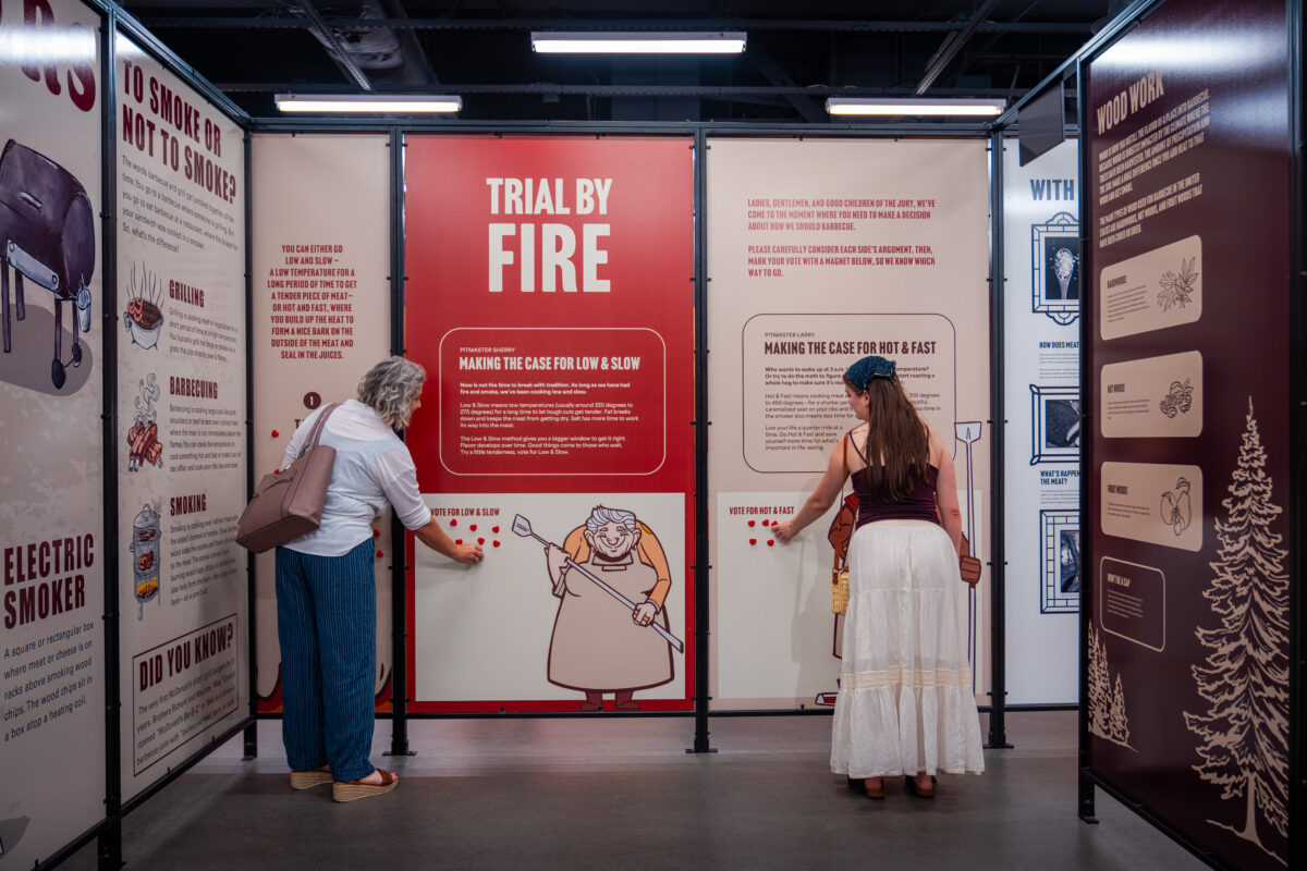 Two women place magnets on a voting wall in the Museum of BBQ.