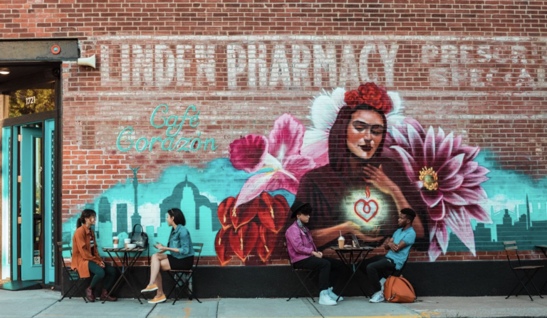 People dine and talk beside a mural.