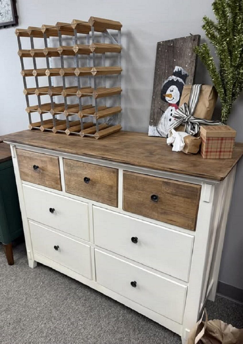 A rustic cabinet, white with three brown drawers on the top row and a brown top.