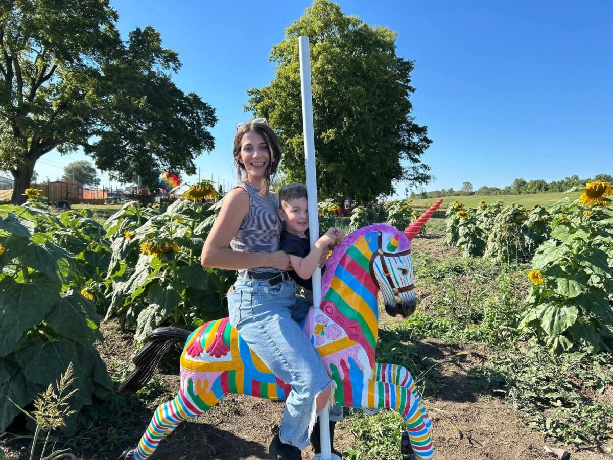 Two people pose on a unicorn statue outside at River City Adventure Park.