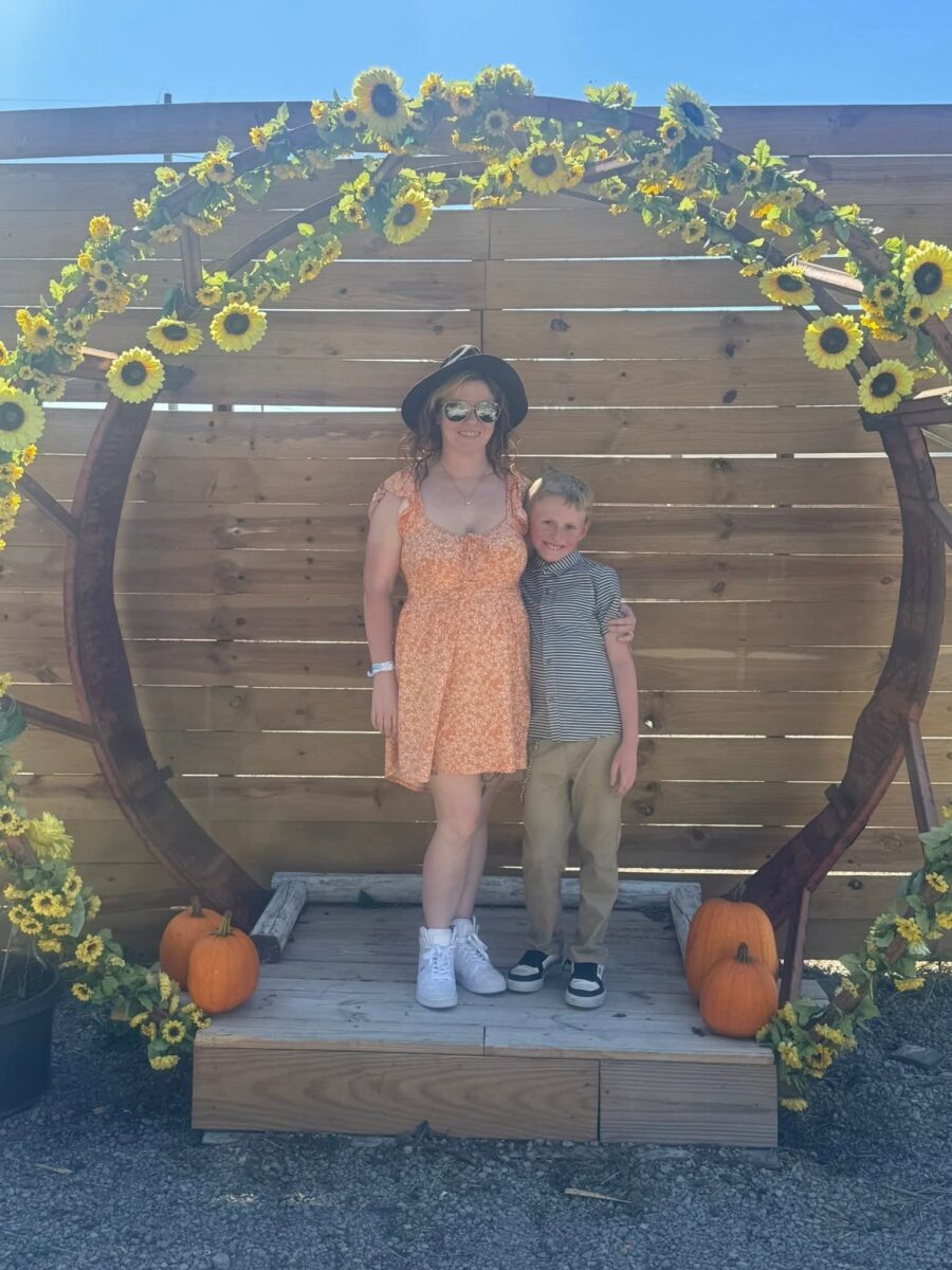 Two people pose beneath a flower arch outside at River City Adventure Park.