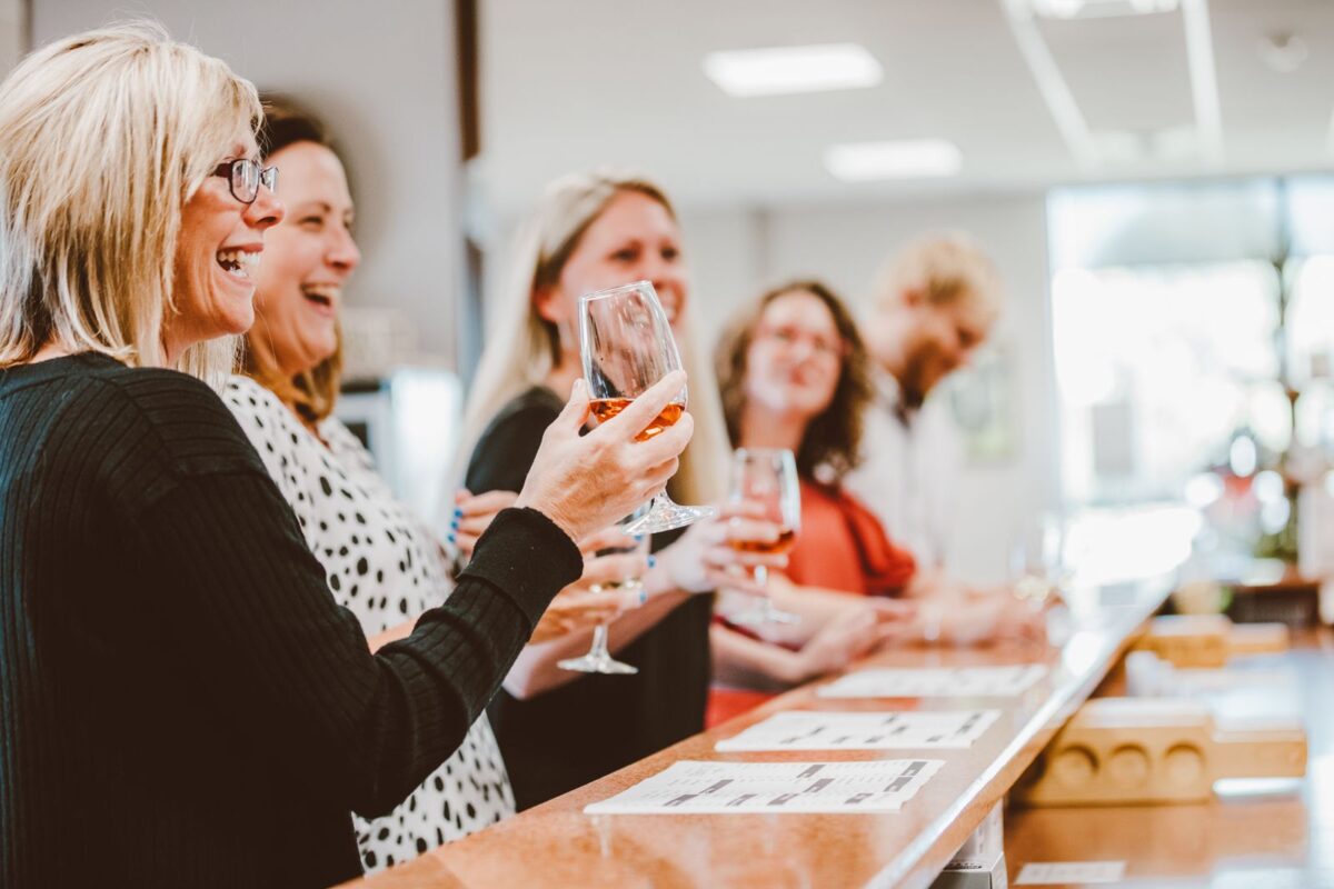 Women drink wine at a bar inside and talk.