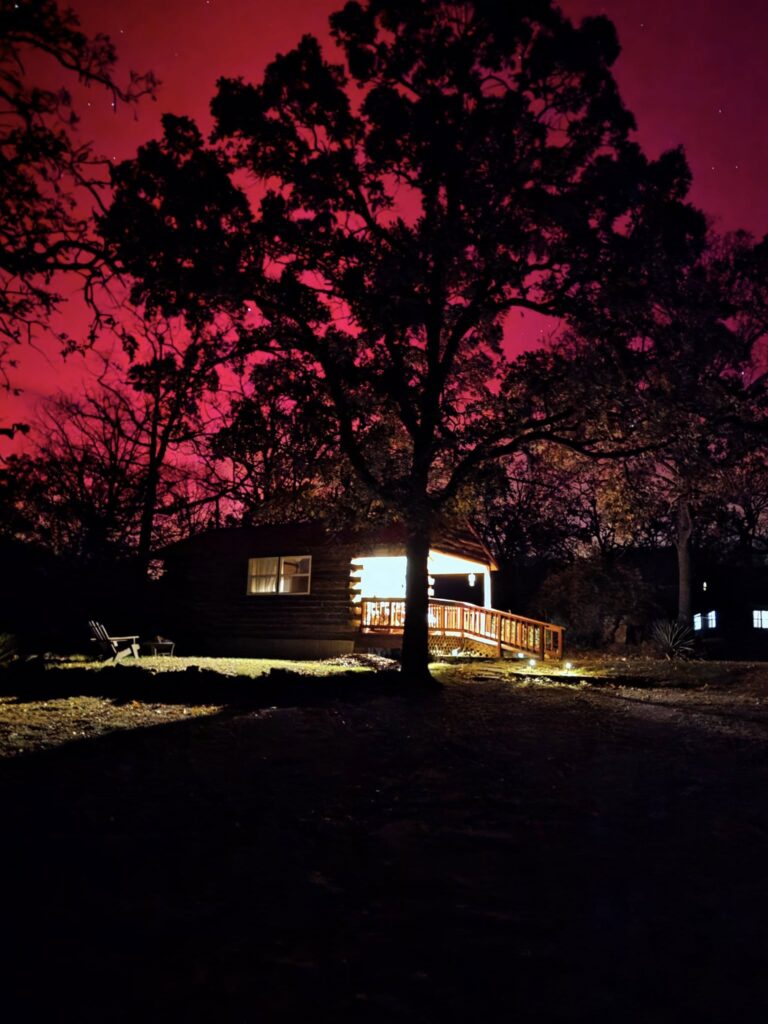 A tree and cabin against a red night sky.
