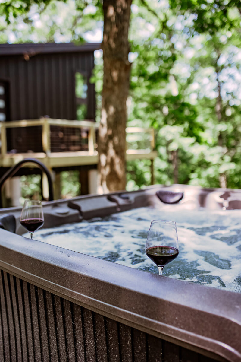 Wine glasses on the rim of a hot tub outdoors.