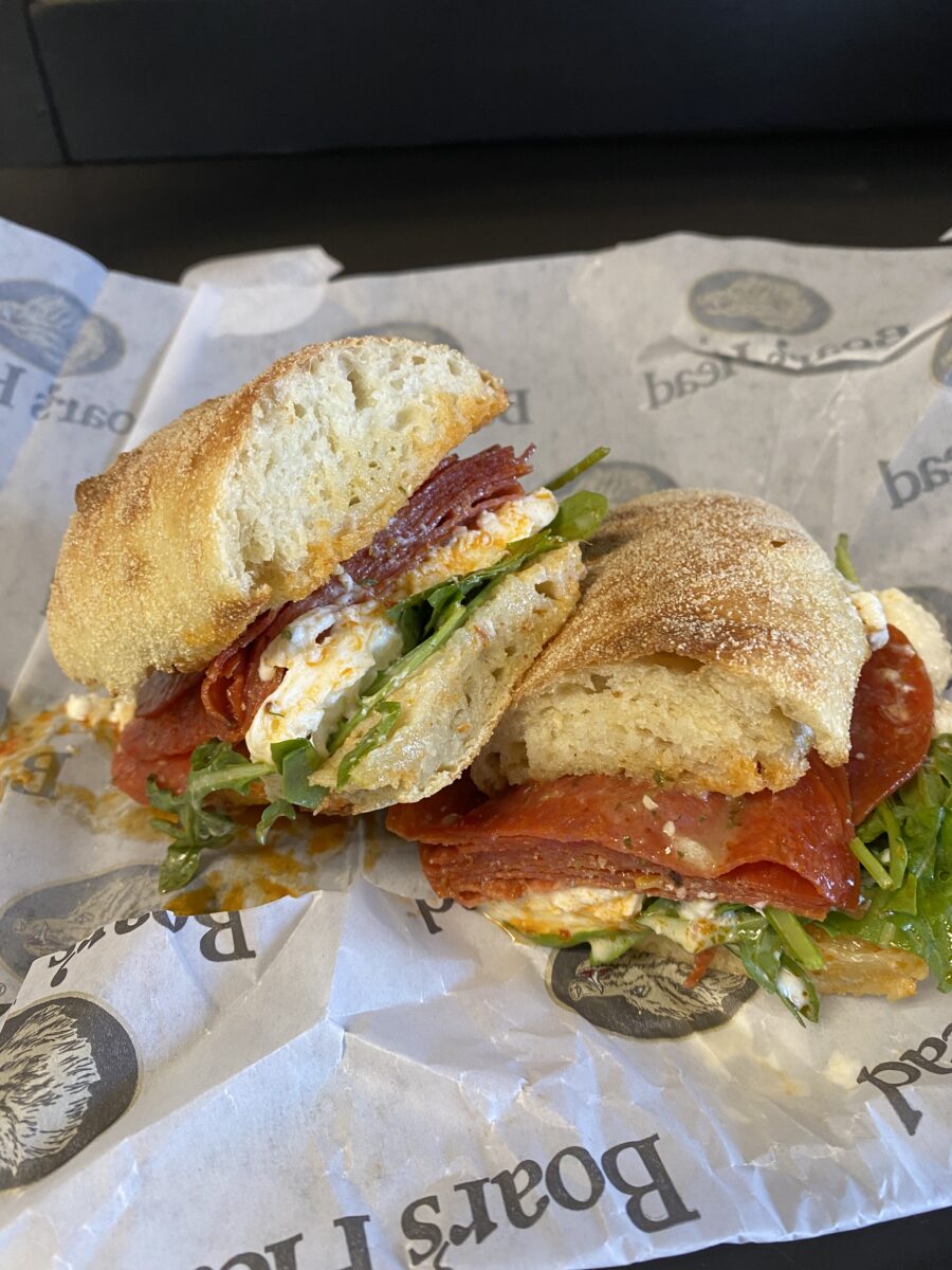 A sandwich cut in half over a branded wrapper.