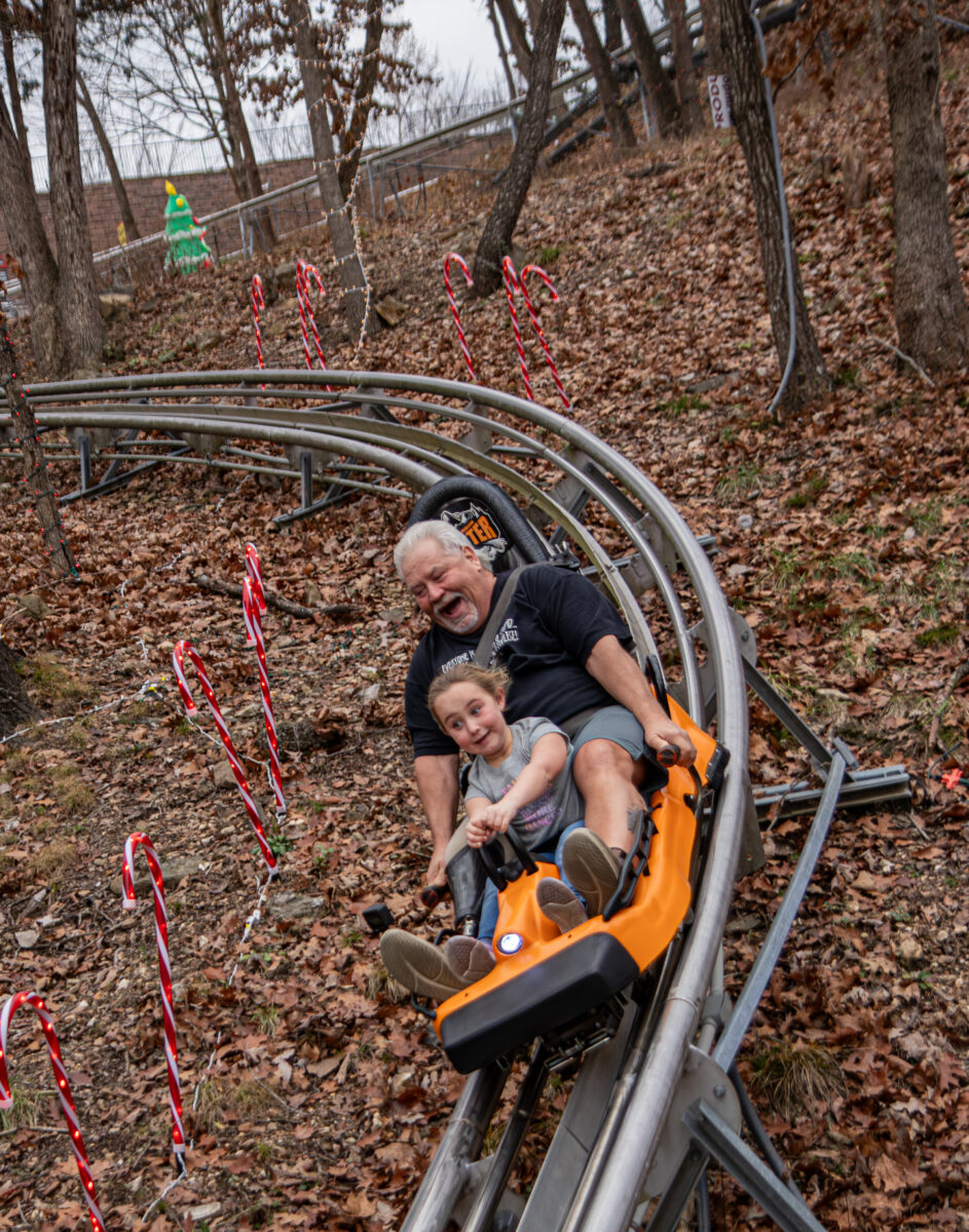 Two people go down a roller coaster in an orange car.