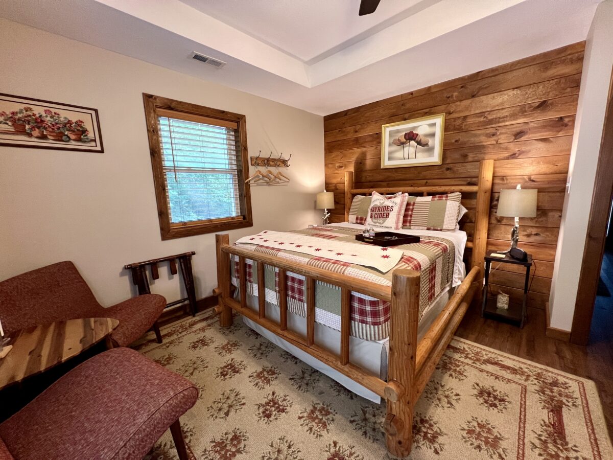 A rustic bedroom with quilts and wood paneling.