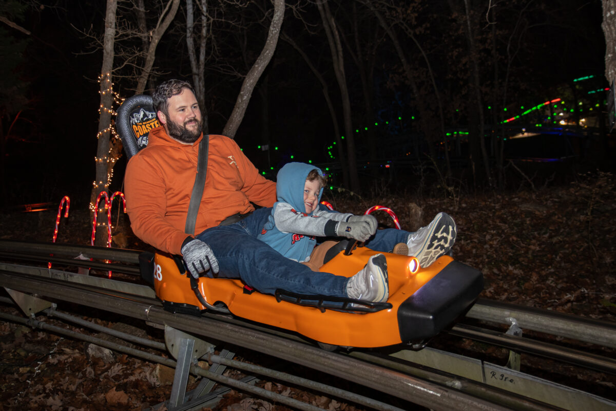 Two people go down a roller coaster in an orange car.