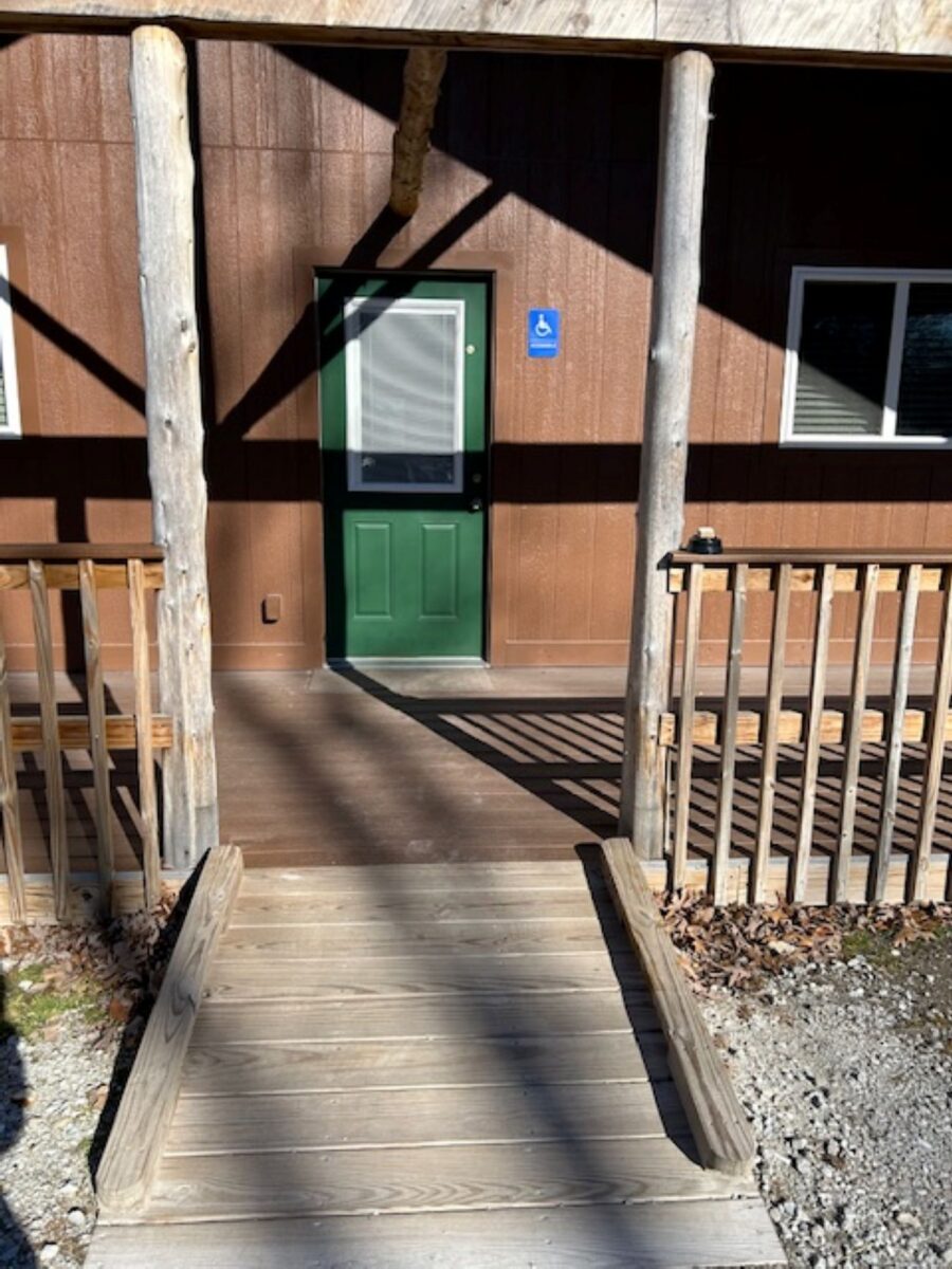 The outside of a brown cabin with a green door.