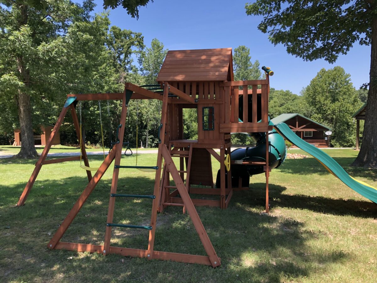 A brown playground with a green slide.