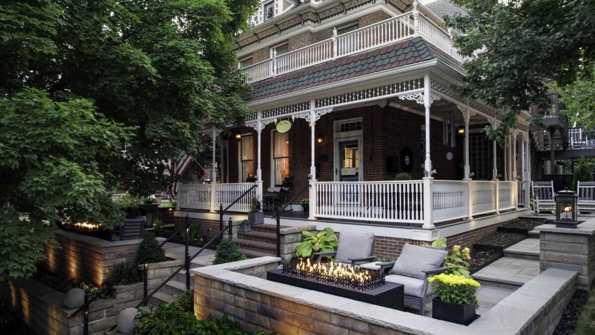 Cozy seating area with a modern fire feature just below the Main Street Inn’s wraparound porch, surrounded by lush trees and historic architecture.