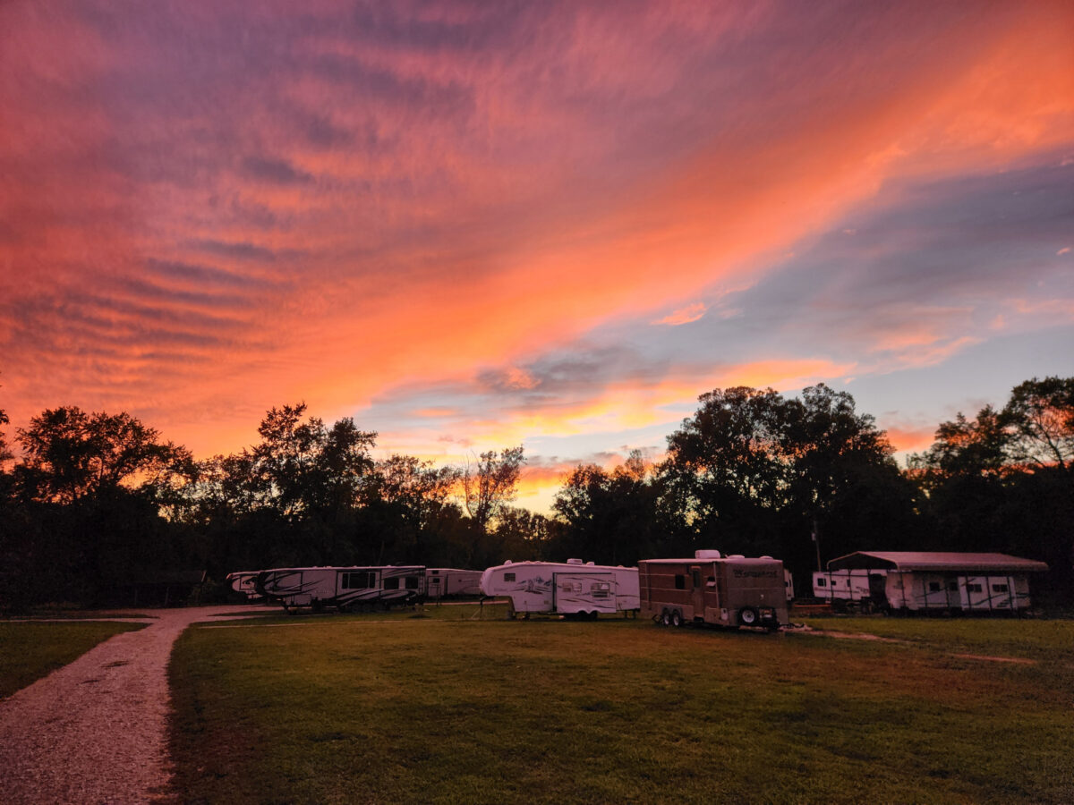 RVs outside of a cabin during a vibrant sunset.