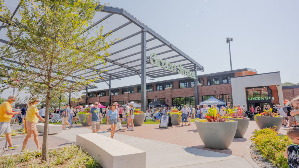 People walk around an outdoor farmers market venue on a sunny day.