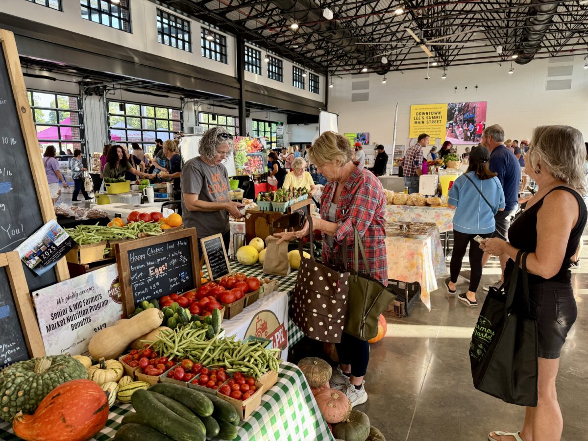 People walk around an indoor farmers market venue checking out produce.