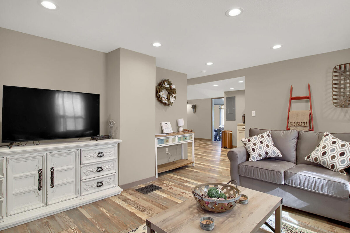 A furnished cottage living room with a couch and love seat, table, and a dresser with a television on top.