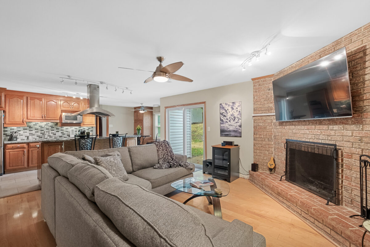 A living room with couches, a fireplace and a large tv.