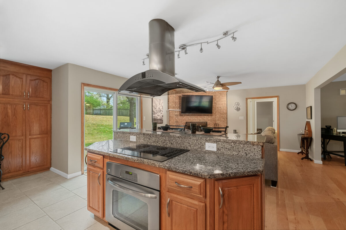 A kitchen with wood tones and a central island with a stove.