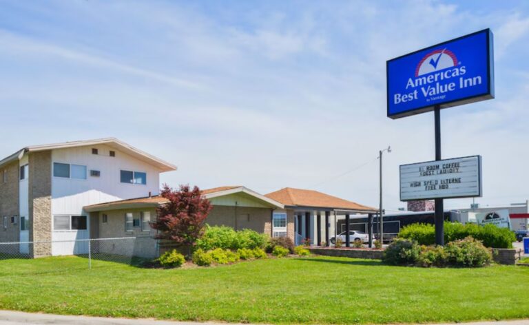 Exterior of the Americas Best Value Inn in Lebanon, Missouri, featuring a two-story building, grassy lawn, and a tall blue roadside sign.