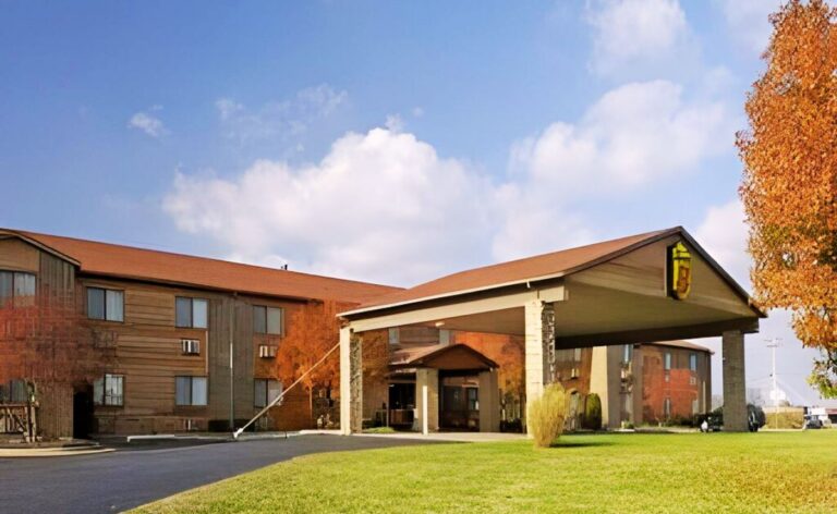 Exterior of a Super 8 hotel in Lebanon, Missouri, featuring a wood-sided building with a green lawn, and autumn trees.